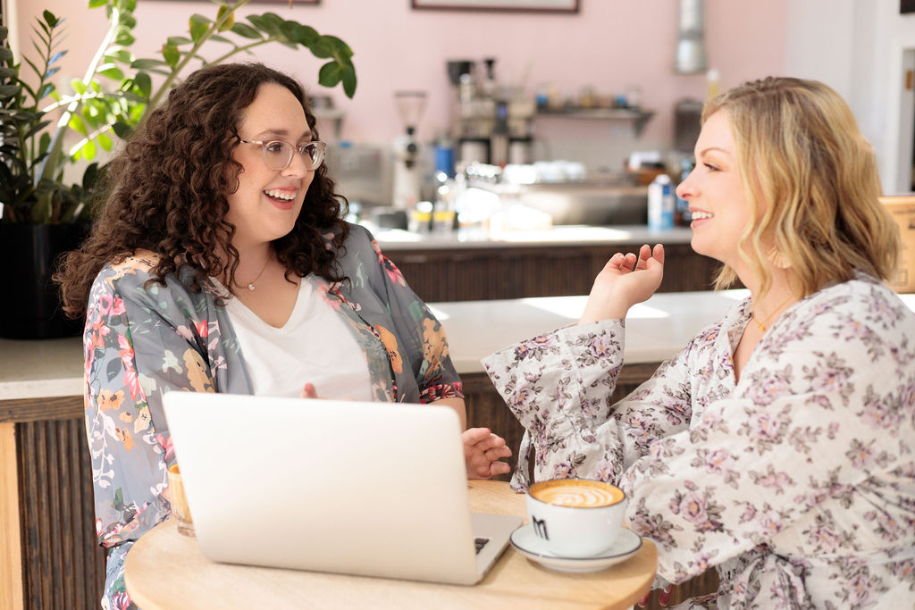 Maureen and Nicole chatting over laptop and coffee